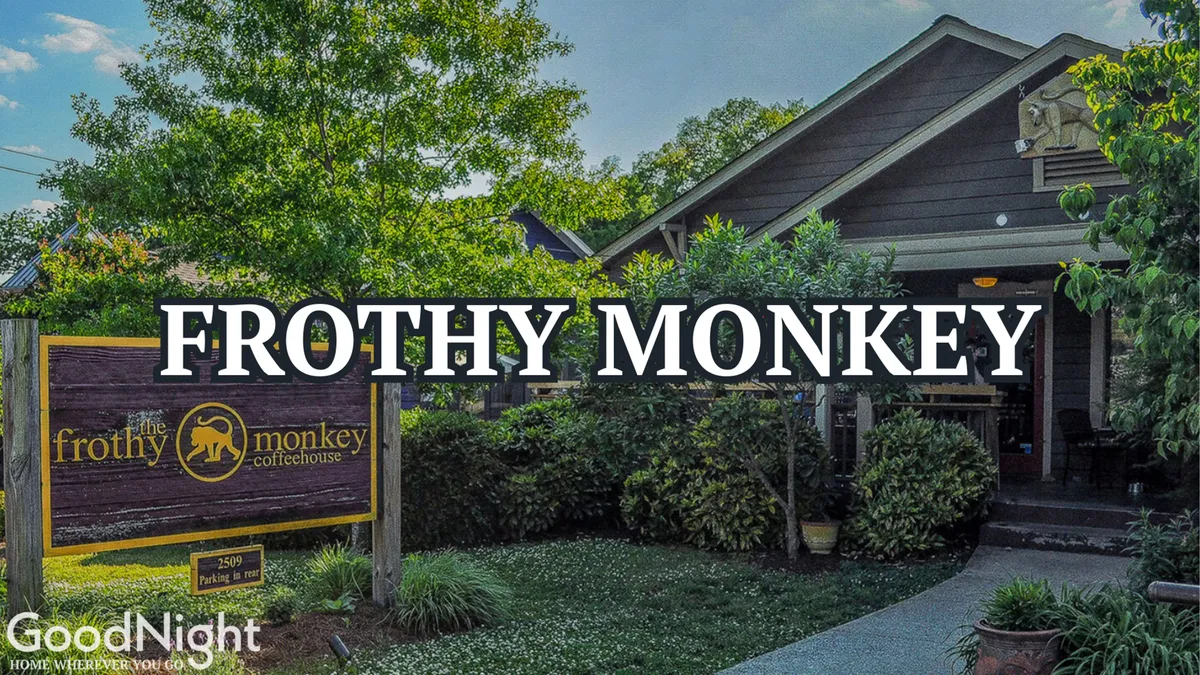 This image displays the inviting exterior of Frothy Monkey, a popular Nashville coffee shop, with prominent signage, wooden facade, and relaxed outdoor seating surrounded by trees and grass. People are seen socializing and enjoying coffee, suggesting a blend of leisure and productivity.