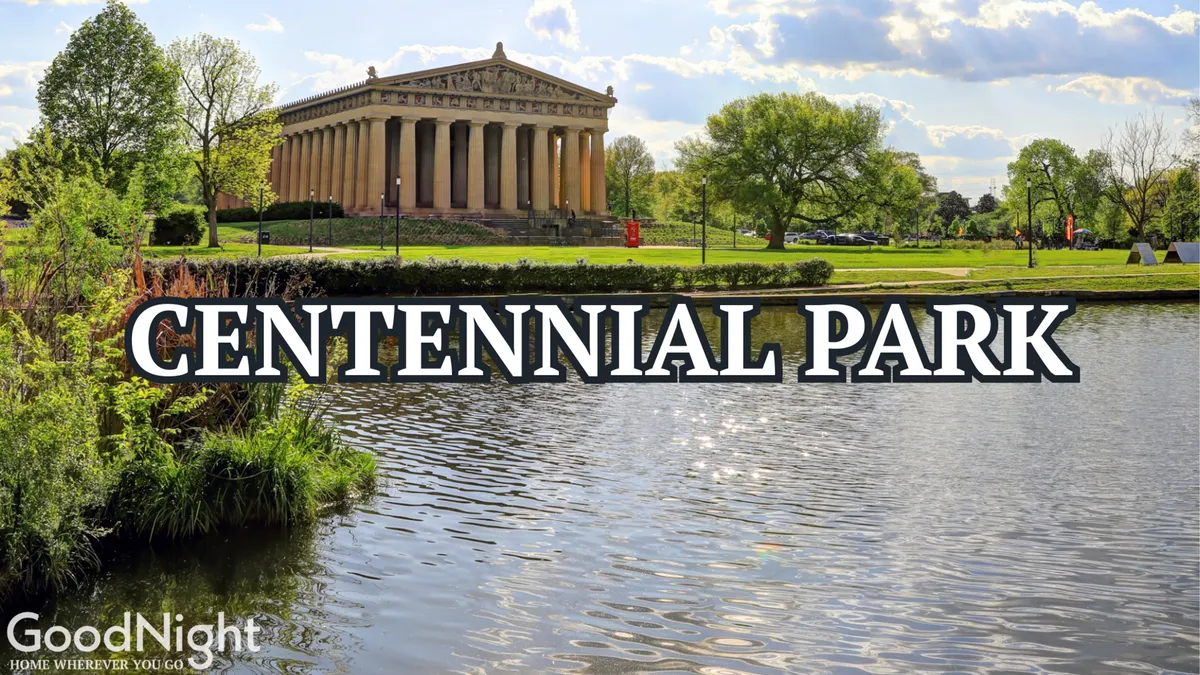 This image captures the iconic Parthenon replica set beside a tranquil pond, surrounded by lush greenery. The calm water reflects the grandeur of the structure, and the nearby open park spaces are visible, inviting visitors to stroll or picnic.